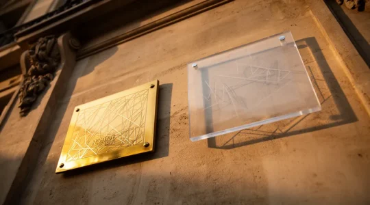 Comparaison de plaques professionnelles en laiton doré et plexiglas transparent sur une façade de cabinet médical